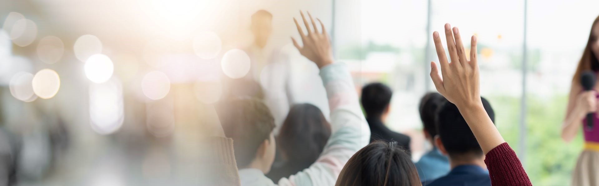People sat in a workshop with their hands raised.
