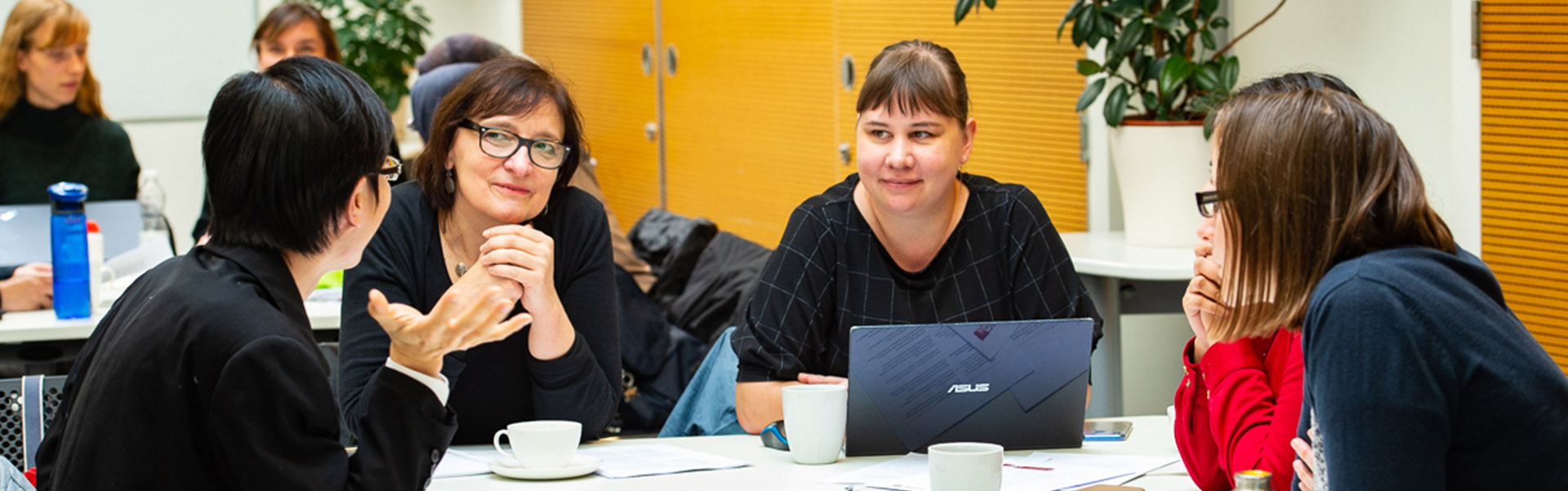Group of colleagues sitting around a table talking in a workshop
