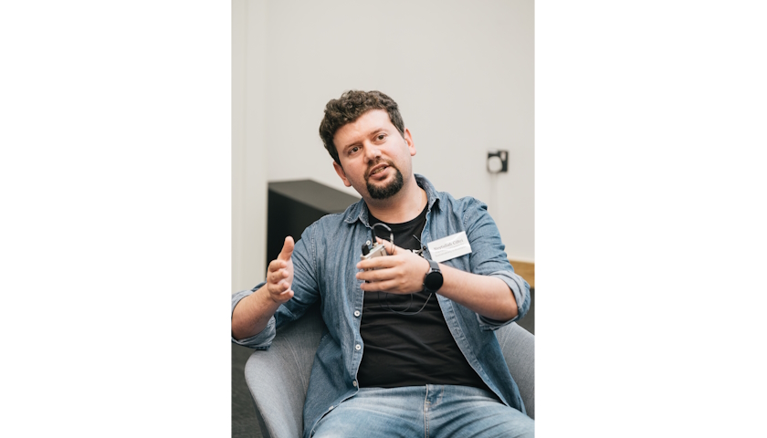 Dr Neytullah Ciftci sitting in a grey armchair, speaking.