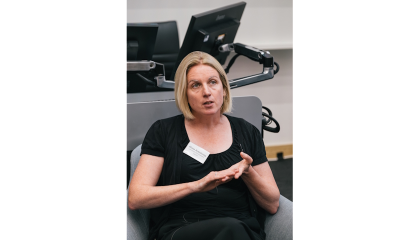 Professor Alona Armstrong sitting in a grey armchair in front of a desk and monitors, speaking