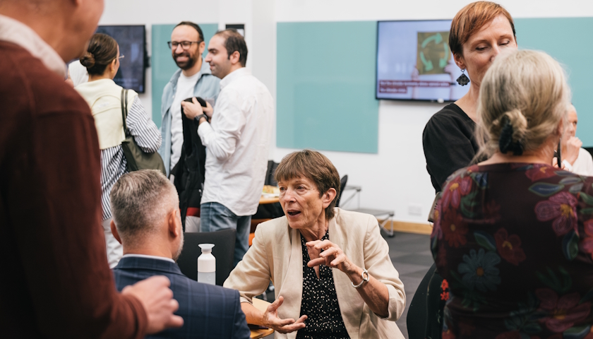  People standing / sitting in groups, in conversation. Centre is Jane Davidson, speaking animatedly