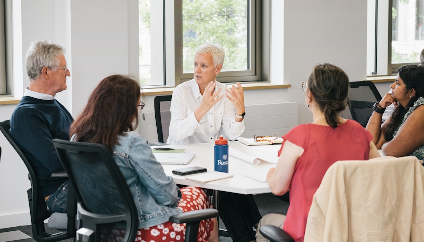 A group of people sitting around a table having a conversation.