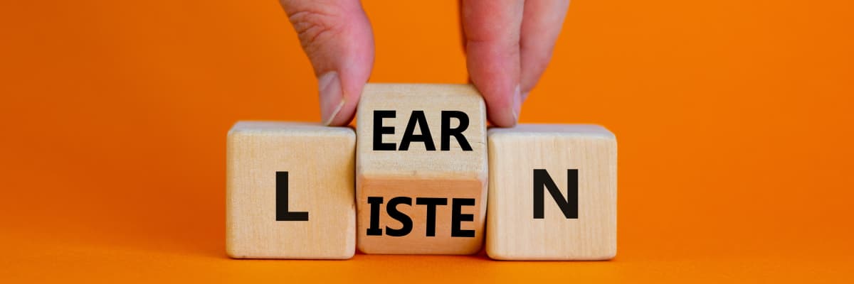 Someone is turning over the middle of three blocks, so the word spelled is either listen or learn.