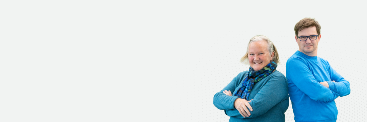 Professor Jan Bebbington and Paul Turner standing back to back smiling at the camera.