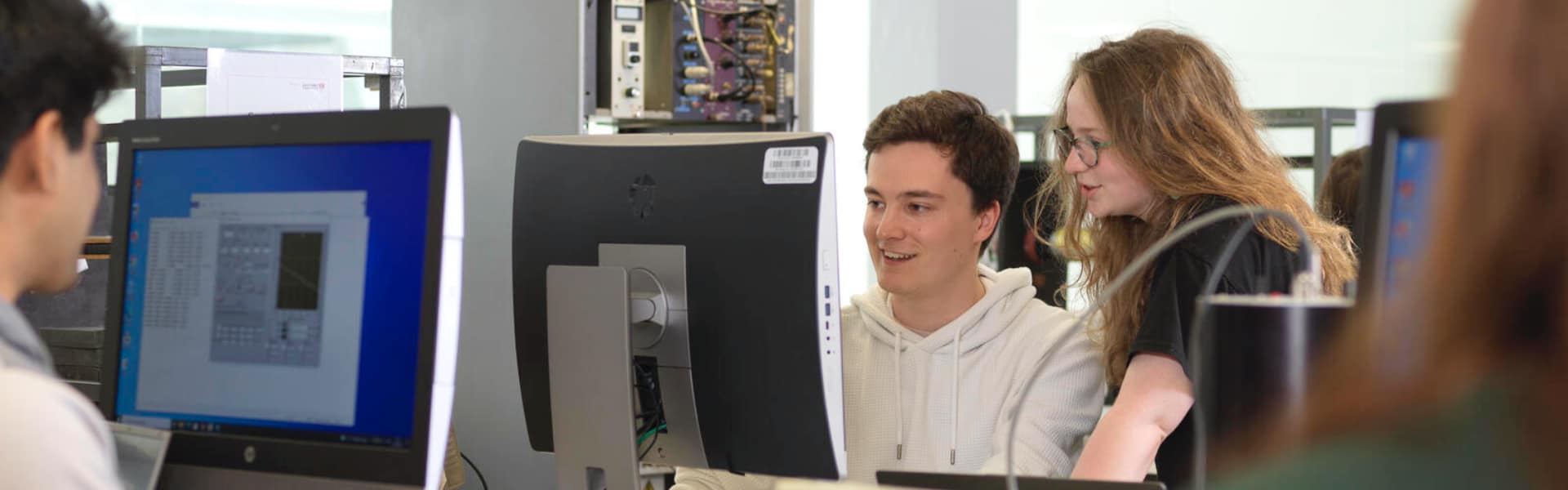 Students in a physics laboratory smile whilst working.