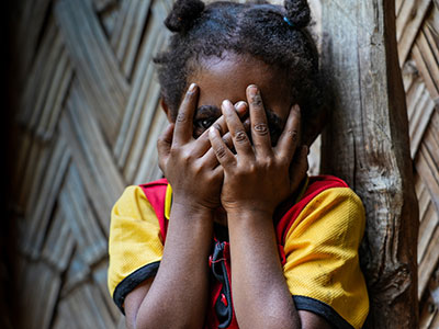 Child hiding face behind their hands