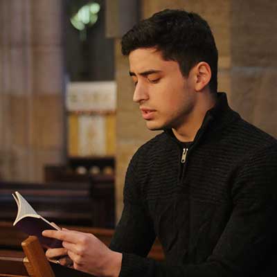 Student doing a reading at the end of term social at the Priory