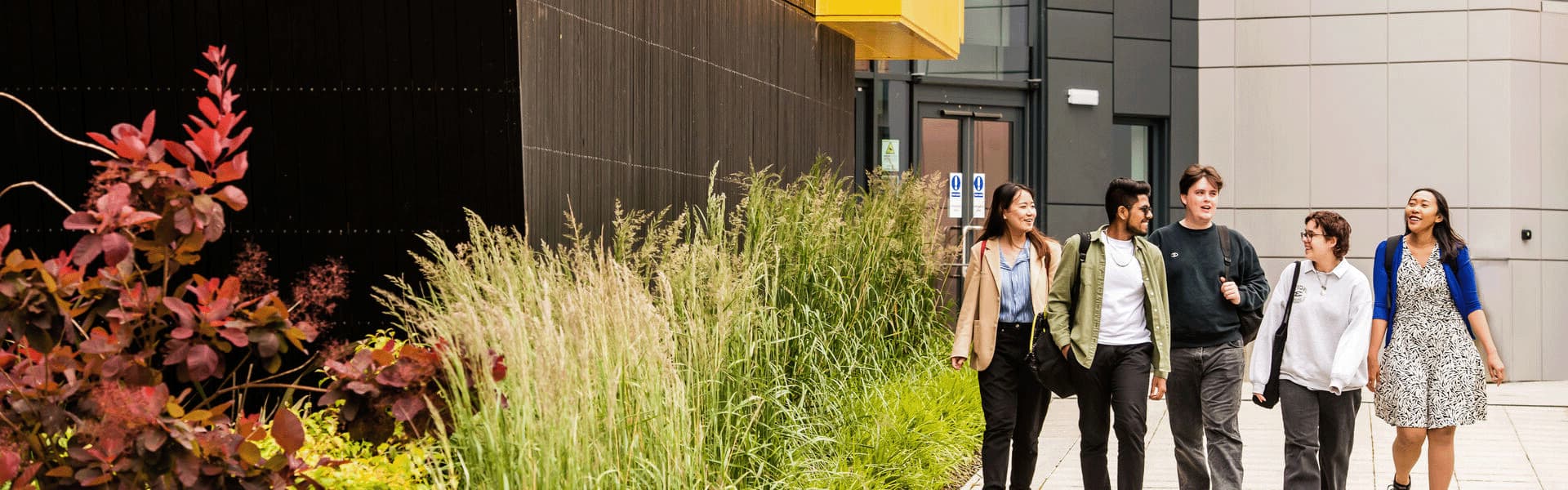 A group of students walking down a ramp next to a black building