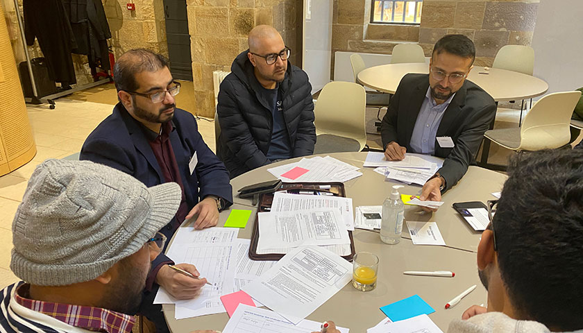 An image of a group of people working around a desk
