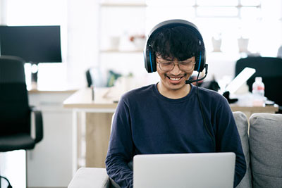 A person in front of a laptop with a head set on