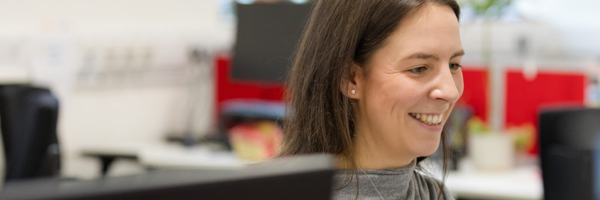A student smiling whilst looking at her computer