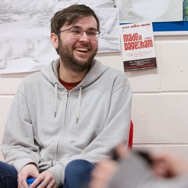 A student smiling to someone off camera, in the communal hub