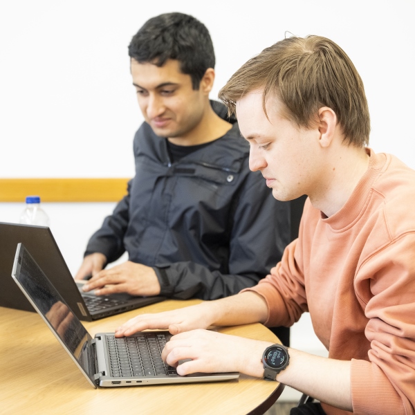 Students sat working together around their laptops 