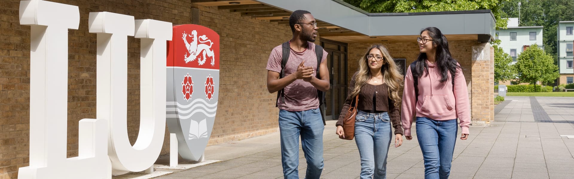 Students sitting ouside in a leafy college quad