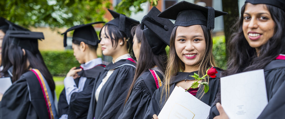 Students smiling at a graduation ceremony.