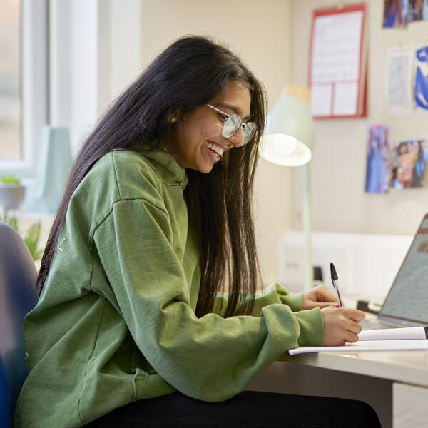 A student works at her desk in her room.