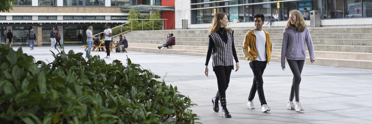 Three students walk across Alexandra Square.
