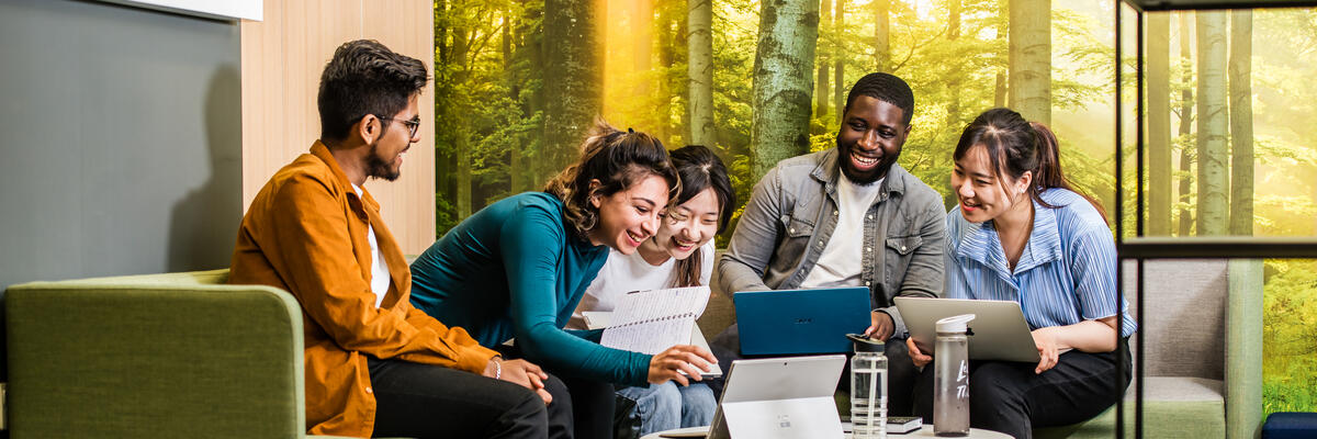 Students sat around a laptop - laughing and talking