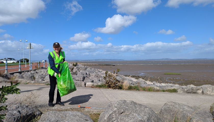 Member of staff on the beach at Morecambe with a litter bag