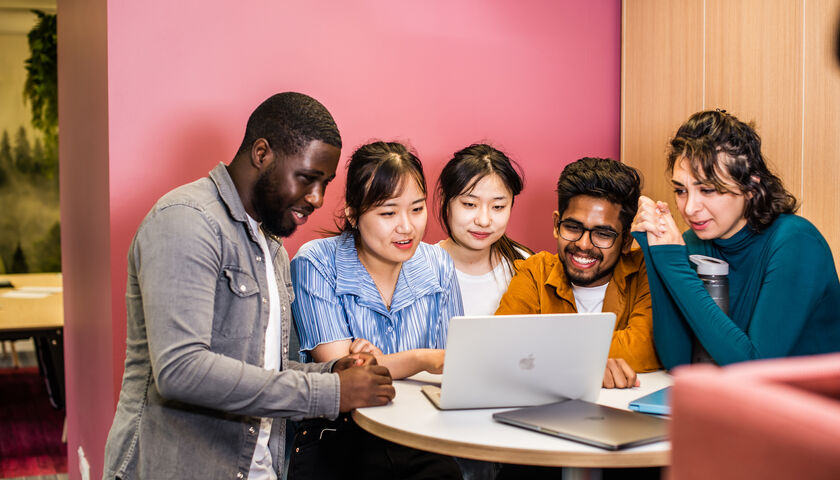 A group of students sat around a laptop
