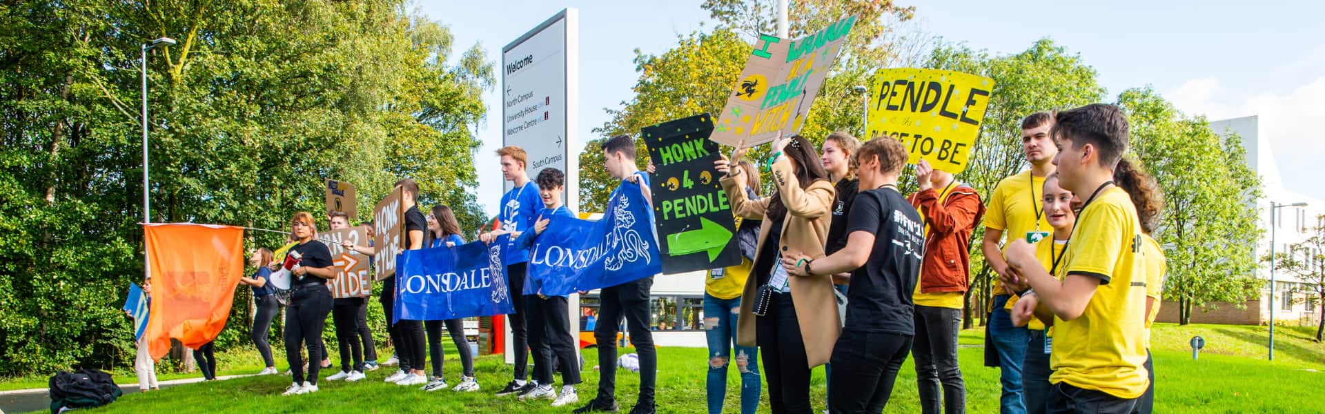 Colleges welcoming arriving students holding banners during arrivals weekend