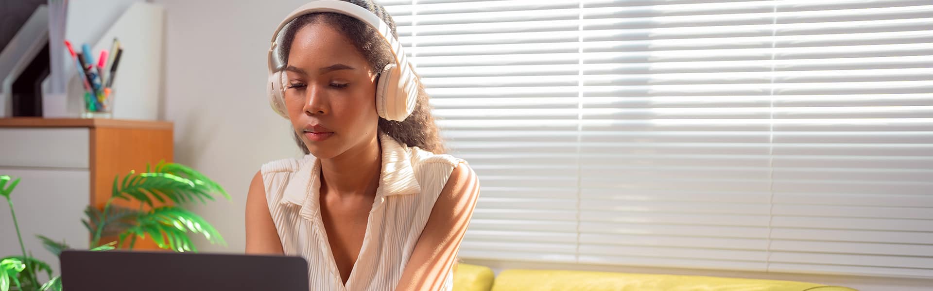 Student sat on a sofa typing on a laptop