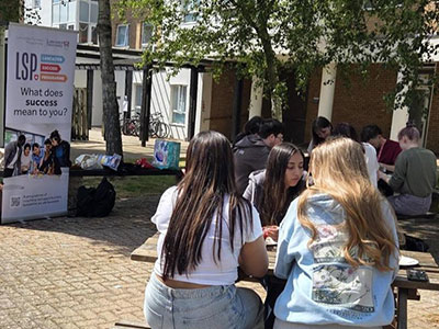 An LSP social with students sitting around benches